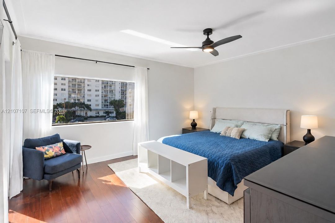 Room featuring wood-finish flooring, a matte black ceiling fan with integrated lighting, and a large horizontal window