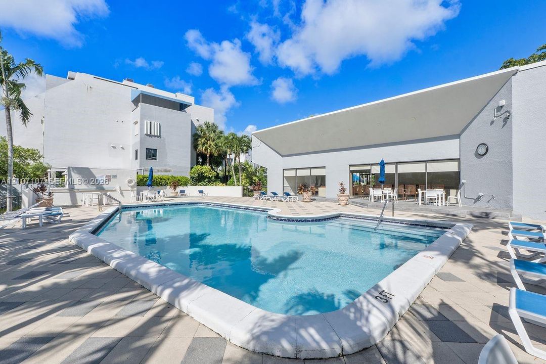 In-ground swimming pool featuring a tiled perimeter and concrete deck with patterned stone pavers