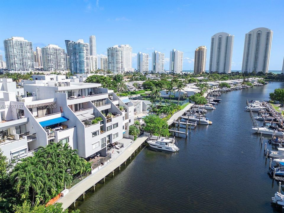 Waterfront multi-level residential structure featuring private boat slips, balconies with overhead sunshades, and concrete bulkhead walk