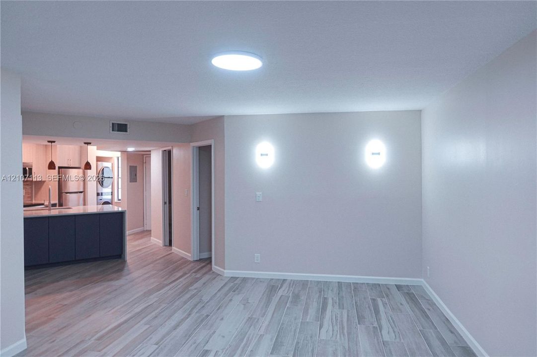 Interior space featuring wood-finish flooring, wall-mounted sconce lighting, and a recessed ceiling light