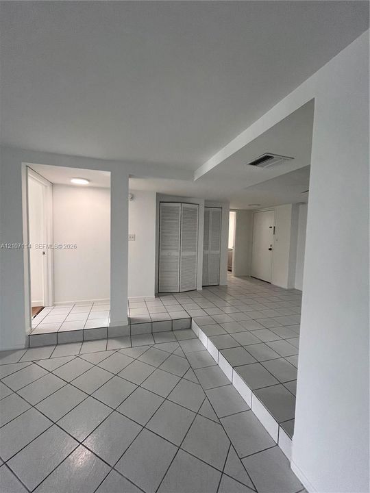 Ceramic tile flooring arranged in a diagonal pattern, elevated platform levels, and dual louvered-door closets
