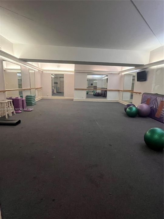 Expansive room featuring wall-to-wall carpeting, integrated full-height wall mirrors, and fixed wooden ballet bars