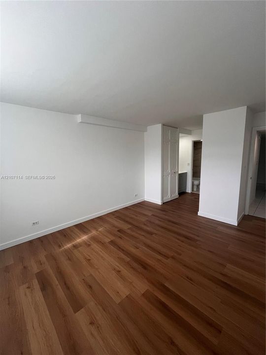 Neutral-toned room featuring wood-finish flooring and floor-to-ceiling bi-fold closet doors