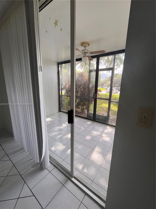 Screened-in porch featuring ceramic tile flooring, a ceiling fan, and sliding glass door entry