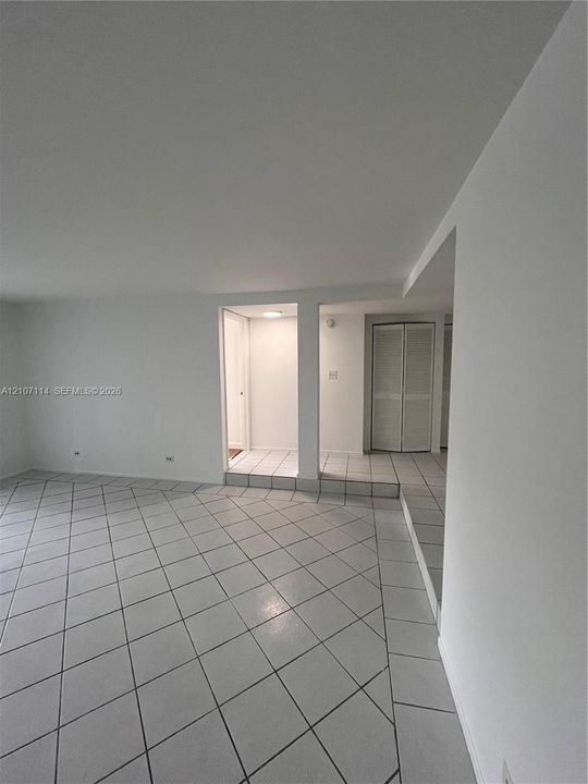 Neutral-toned ceramic tile flooring laid in a diamond pattern, multi-level flooring elevation, and built-in closet with louvered doors