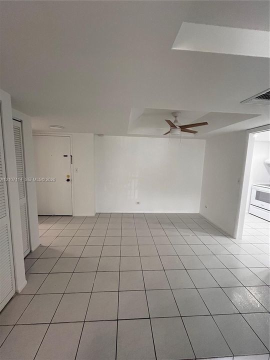 Ceramic tile flooring, tray ceiling with a mounted ceiling fan, and louvered closet doors