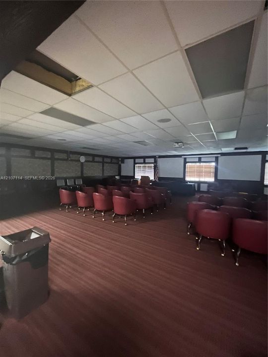 Expansive room featuring a drop ceiling with integrated lighting, wood-paneled walls with decorative trim, and wall-to-wall carpeting