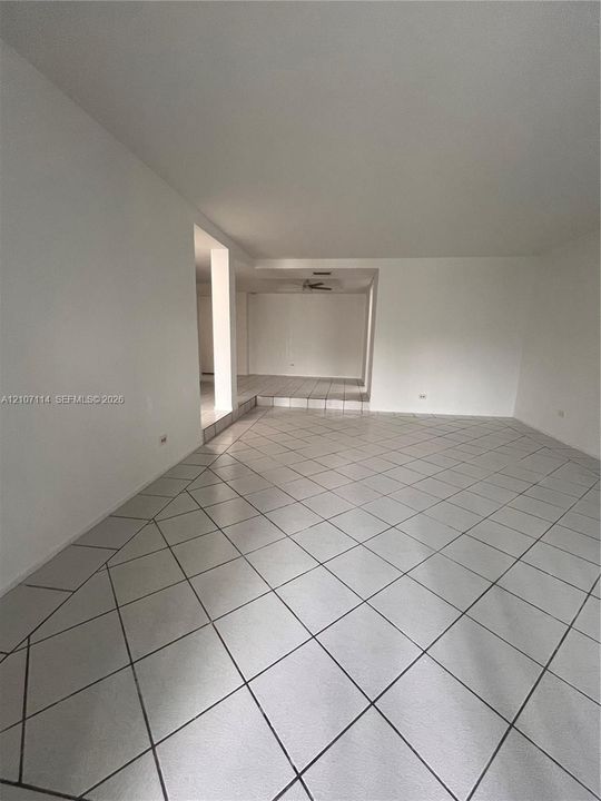 Interior space featuring white walls, neutral diagonal-set tile flooring, and a multi-level floor plan with a stepped platform