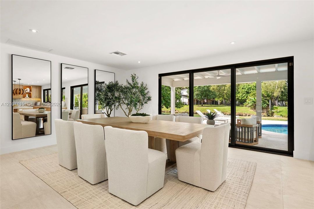Open-concept interior featuring large-format tile flooring, recessed lighting, expansive multi-panel sliding glass doors, and three floor-to-ceiling wall mirrors