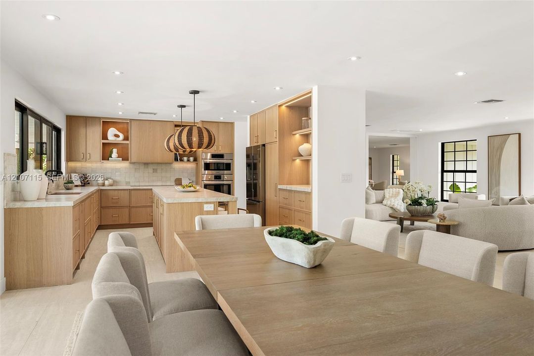 Custom wood cabinetry with integrated lighting, stone countertops, stainless steel built-in double ovens, recessed lighting, and large-format tile flooring