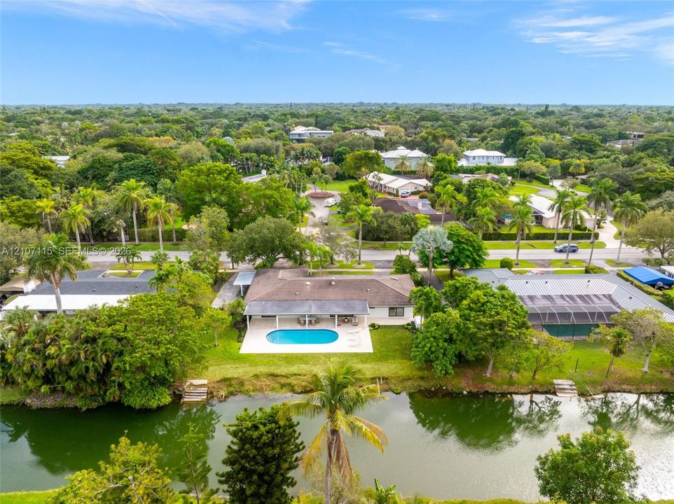 Waterfront property featuring a swimming pool, covered concrete patio, and direct canal access with bulkhead