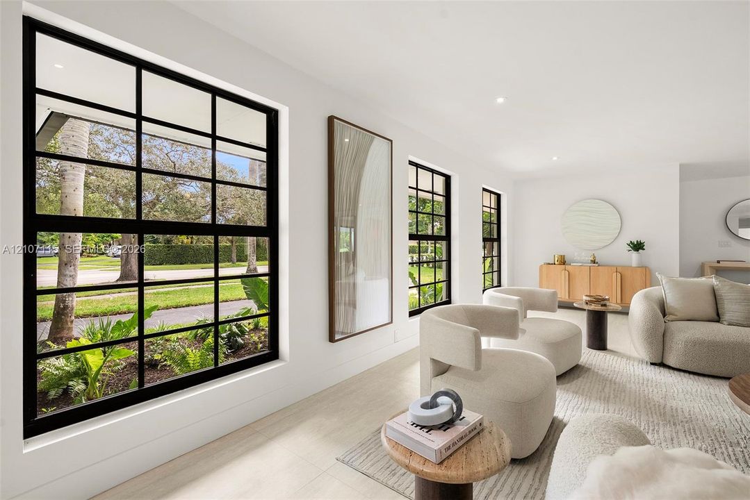 Expansive interior space featuring large multi-pane windows with black frames, recessed ceiling lighting, and light-toned wood-finish flooring