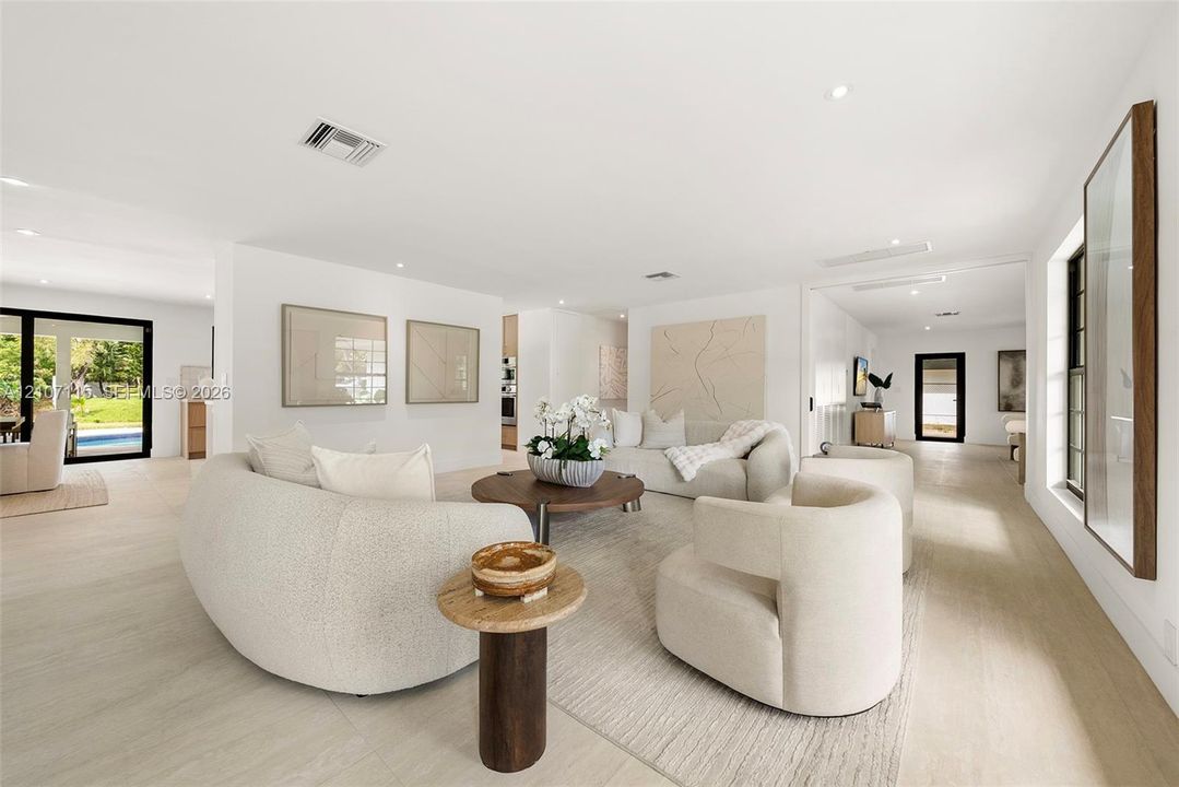 Open-concept interior featuring light-toned wood-finish flooring, recessed lighting, and expansive glass doors