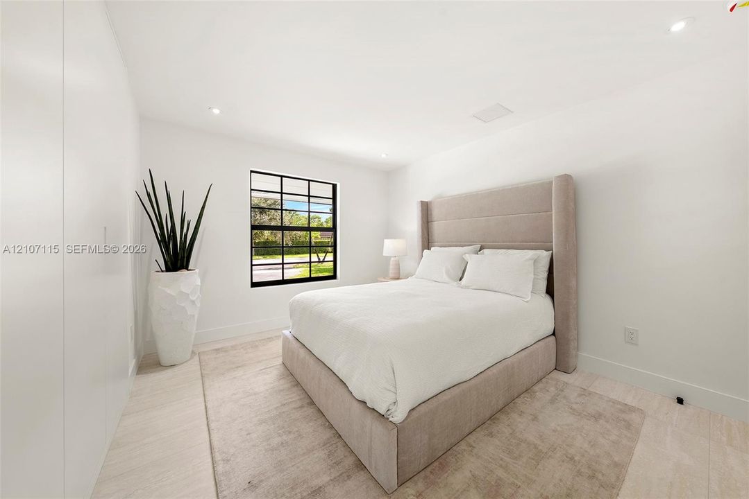 Bedroom 3 Minimalist room featuring smooth white walls, recessed ceiling lighting, light-toned tile flooring, and a black-framed grid window