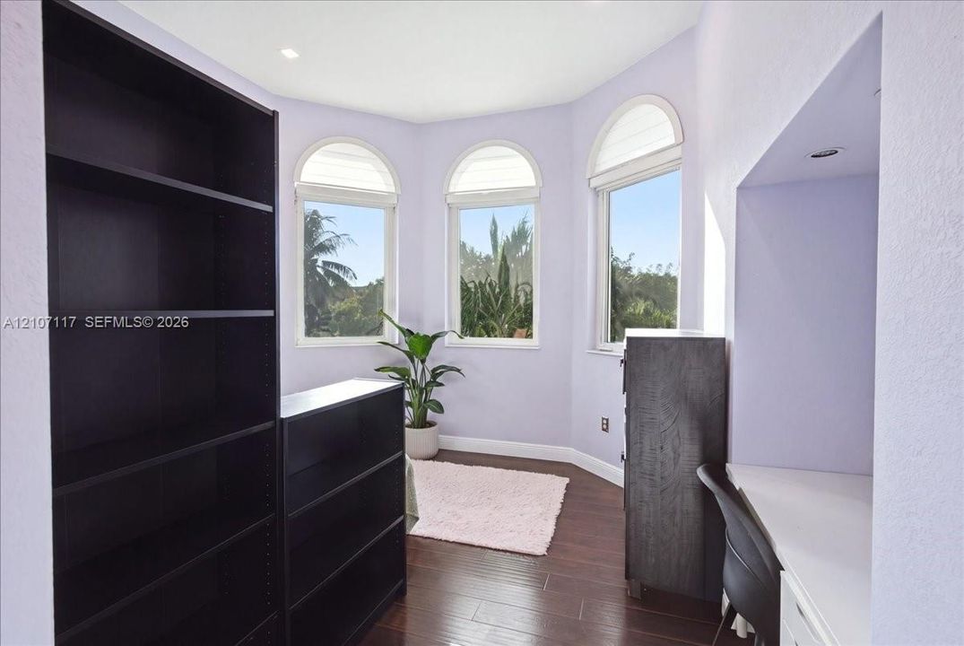 Bay window featuring three arched-top windows and recessed ceiling lighting with dark wood-finish flooring and a built-in desk surface