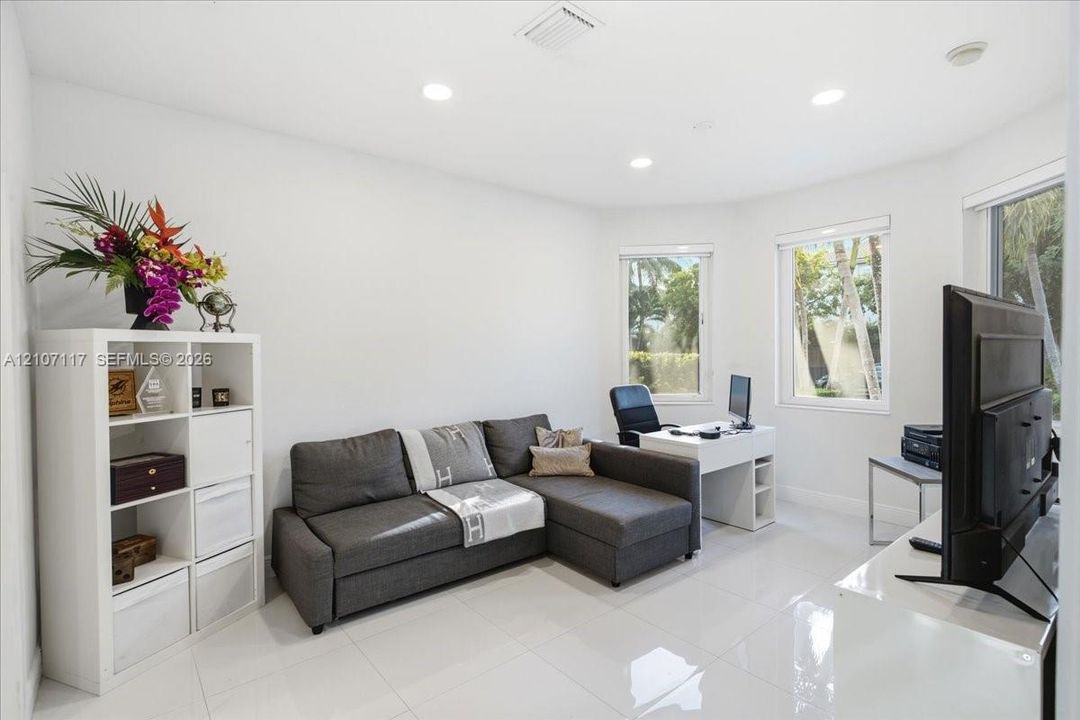 Neutral-toned interior featuring large-format tile flooring, recessed ceiling lighting, and expansive bay windows
