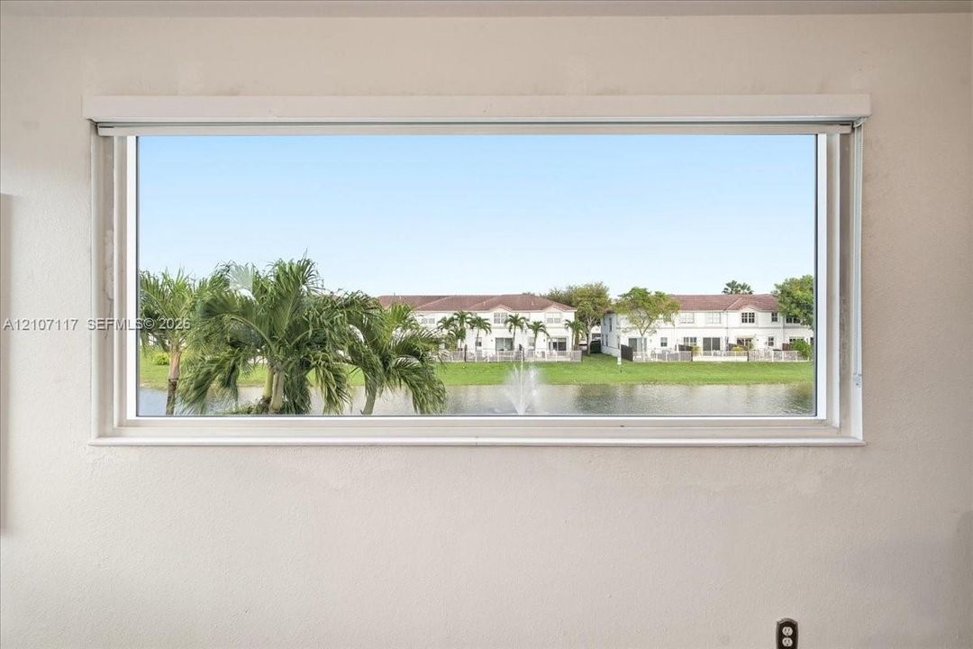 Horizontal window frame featuring a water feature, palm trees, and residential scenery