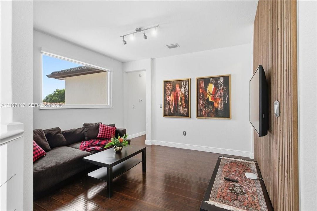 Interior space featuring wood-finish flooring, a decorative vertical slat wood wall, and a multi-bulb track lighting fixture