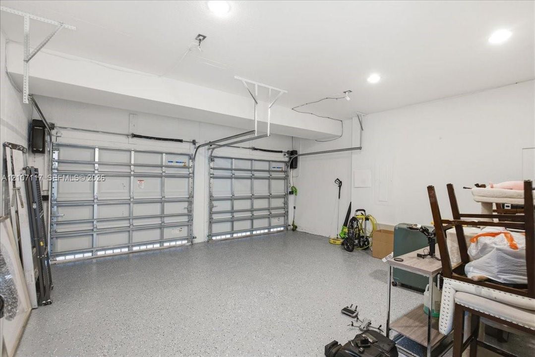 Two-car garage featuring dual overhead metal doors, neutral wall finish, recessed lighting, and durable flecked-epoxy flooring