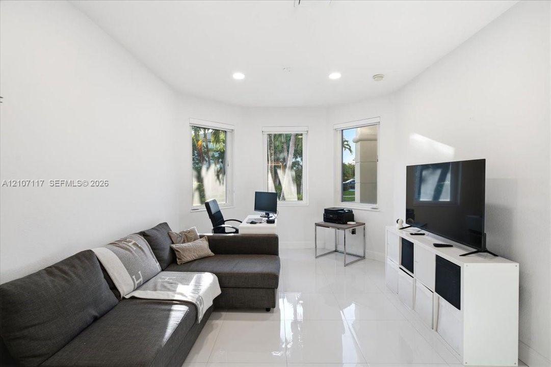 Bright room featuring glossy tile flooring, three large windows, and recessed lighting