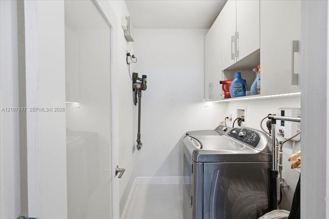 Laundry room featuring flat-panel upper cabinetry, under-cabinet task lighting, and neutral tile flooring