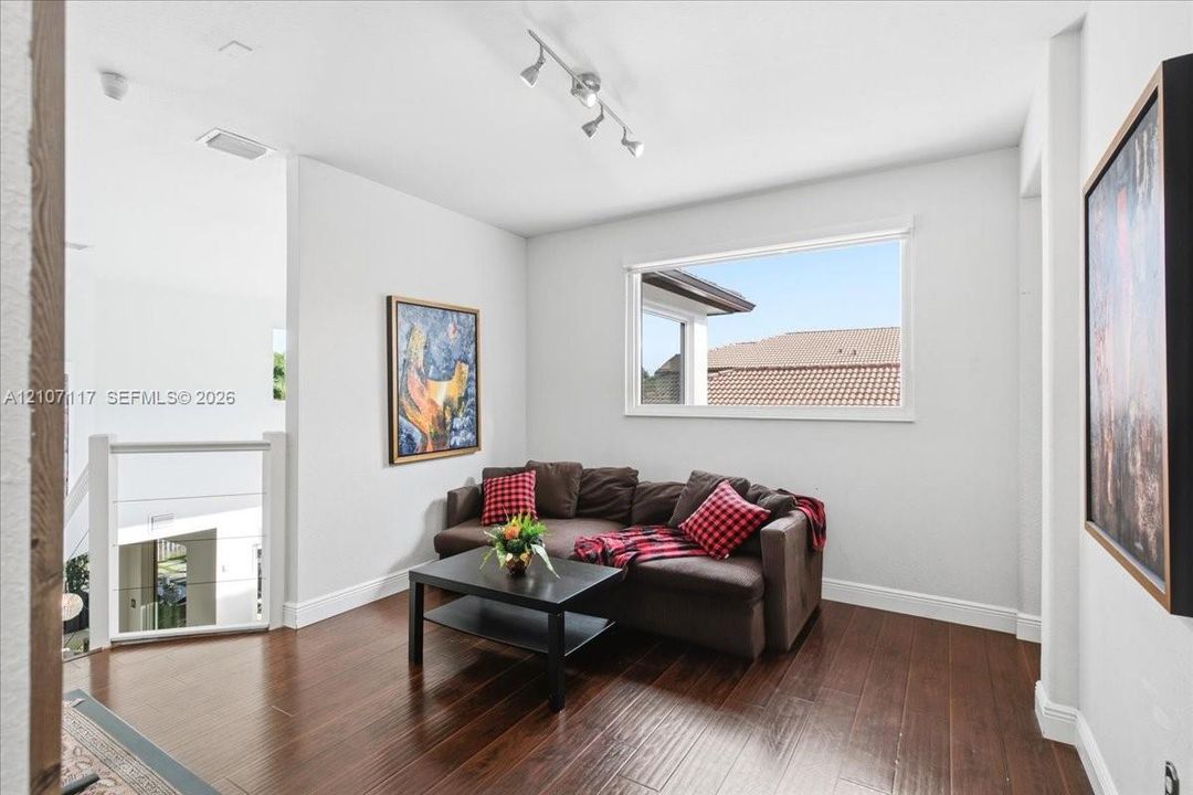 Wood-finish flooring, white walls, multi-directional track lighting, and a horizontal window with exterior trim