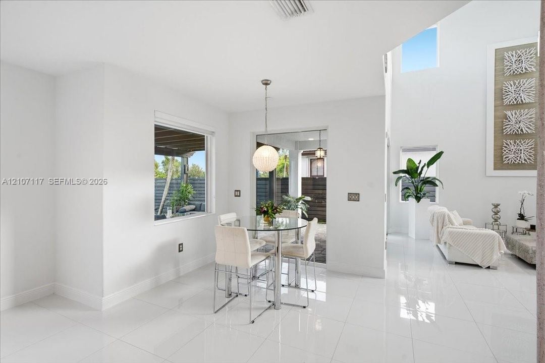 Open-concept space featuring polished tile flooring, soaring vaulted ceilings, expansive windows, and a modern spherical pendant light fixture