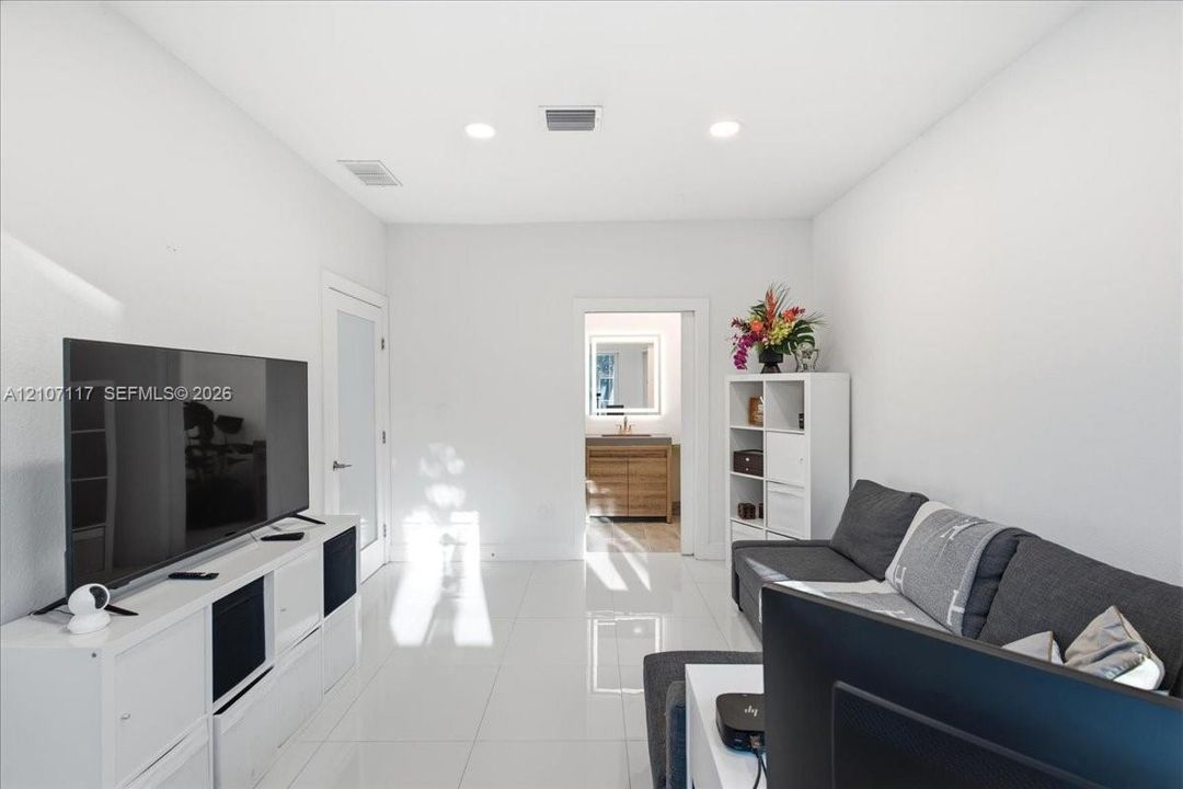 High-gloss porcelain tile flooring, recessed ceiling lighting, and a frosted glass-panel interior door