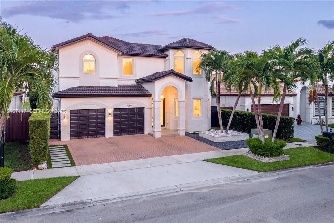 Two-story Mediterranean-style exterior featuring a tile roof, arched entryway, stucco facade, and an attached two-car garage with a paved driveway