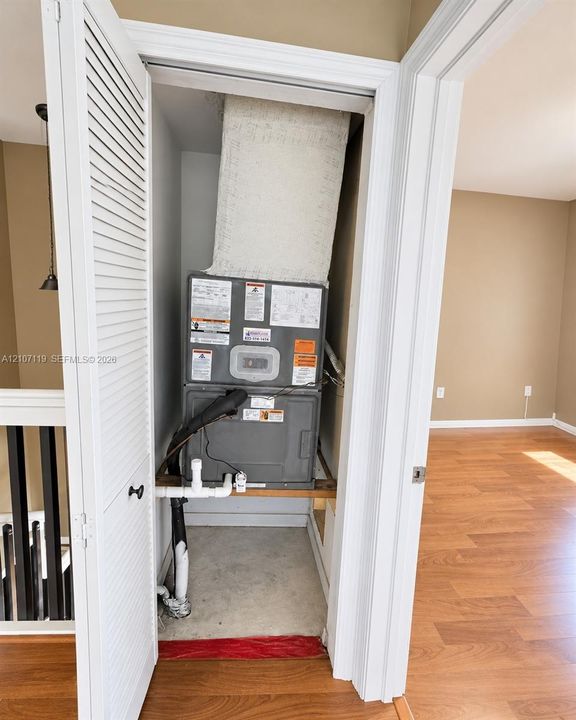Utility closet housing a forced-air furnace unit with louvered doors