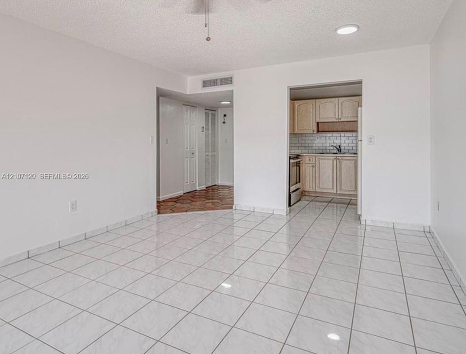 Open floor plan featuring large-format ceramic tile flooring, recessed lighting, and a kitchen equipped with wood cabinetry and a subway tile backsplash