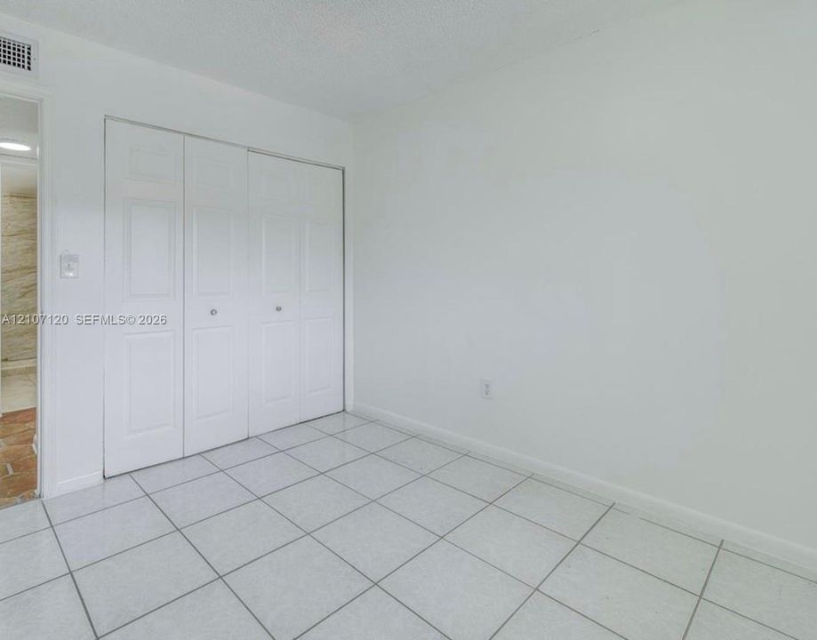 Interior room featuring white tile flooring and floor-to-ceiling bi-fold closet doors