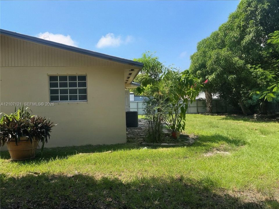 Backyard exterior featuring a paved stone patio, mature landscaping, and perimeter fencing