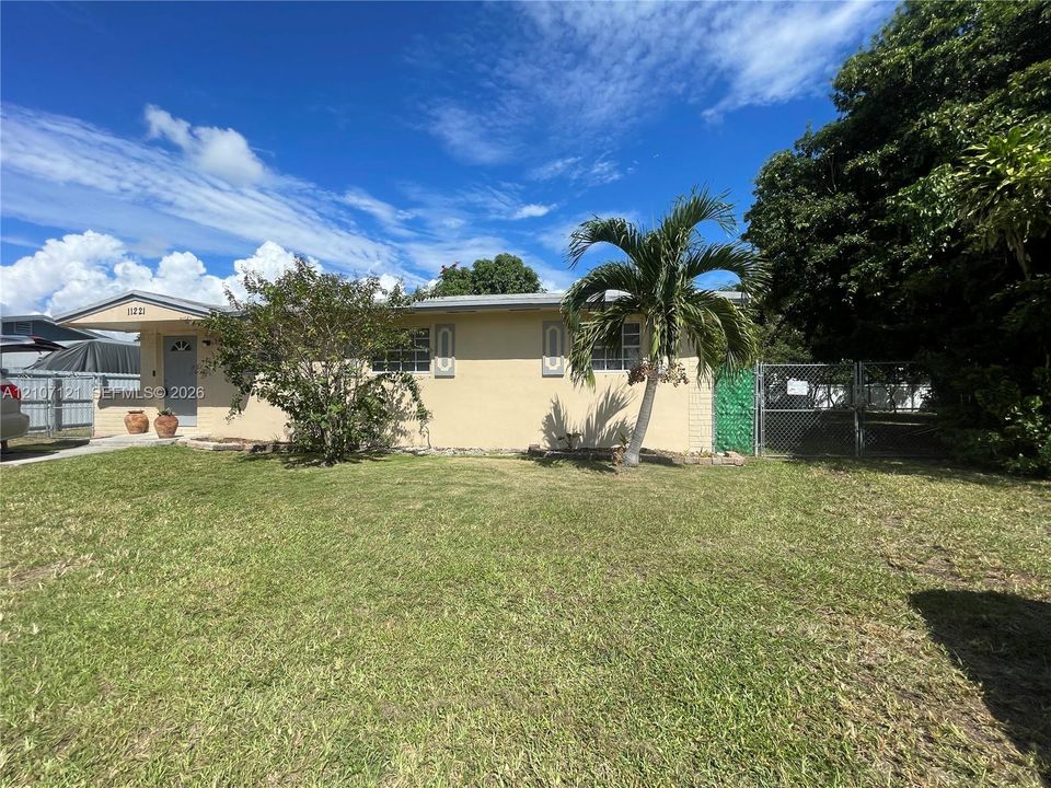 Single-story residence featuring a stucco exterior, concrete driveway, front yard landscaping, and gated side enclosure