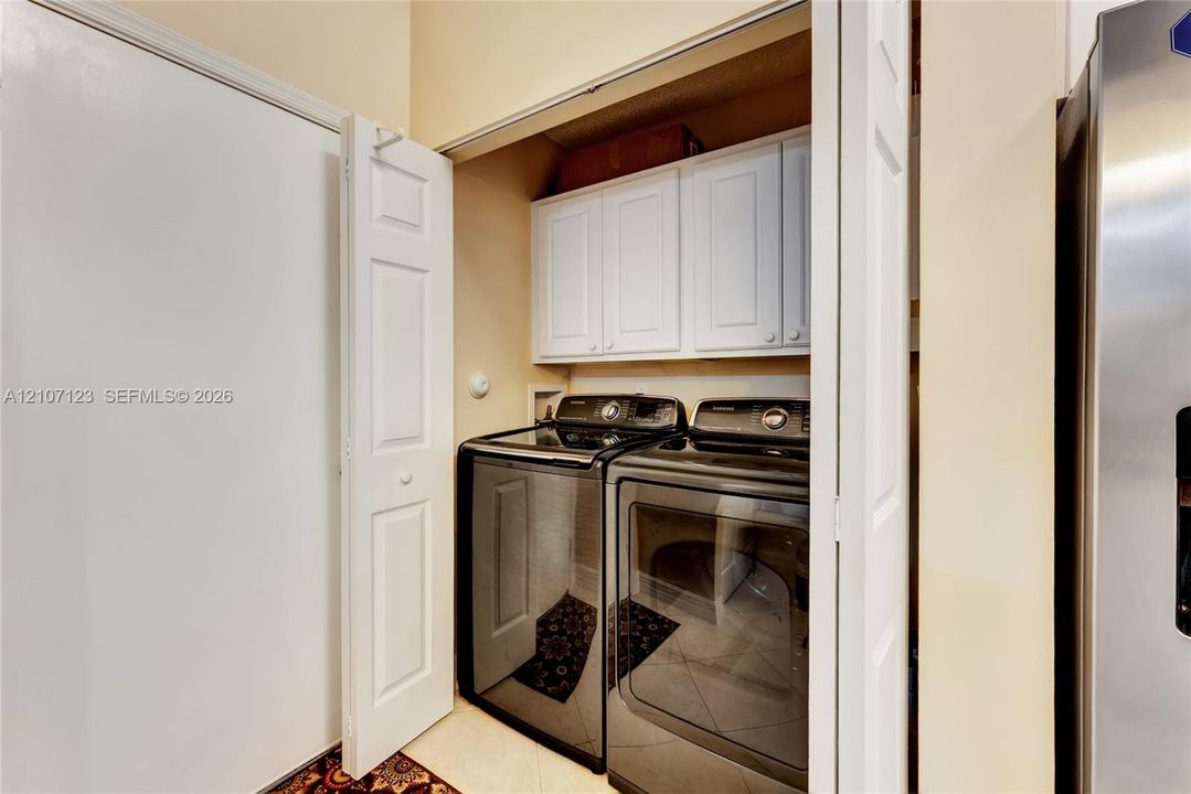 Laundry closet featuring white built-in upper cabinetry and bi-fold doors