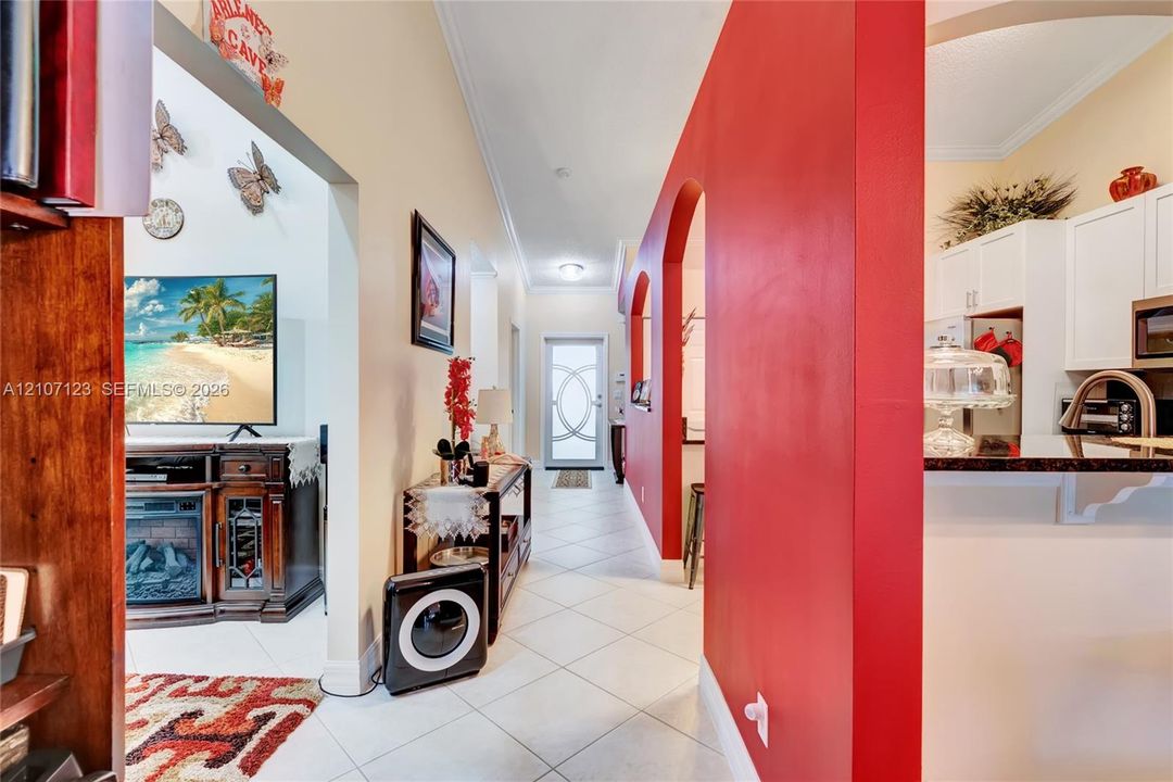 Interior entry featuring tile flooring, arched wall openings, a decorative glass-paneled entry door, and white cabinetry