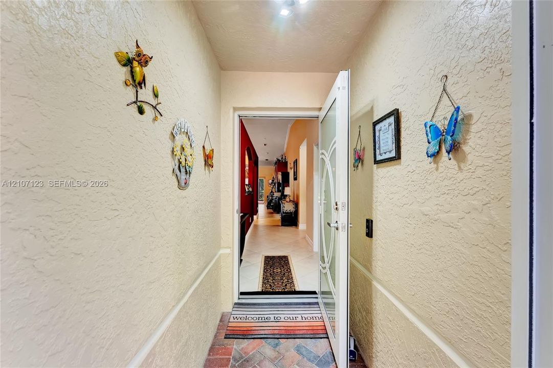 Entryway featuring a herringbone-patterned brick floor, textured wall finish, and a glass-inset entry door