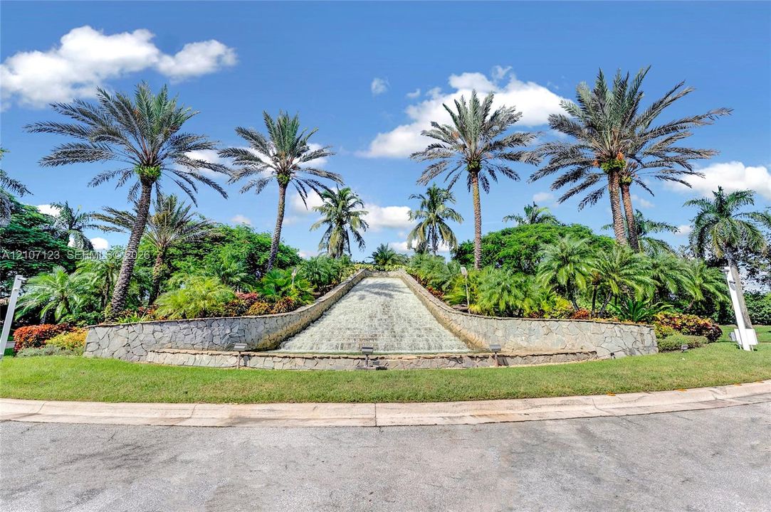 Stone-clad water feature surrounded by lush tropical landscaping and mature palm trees