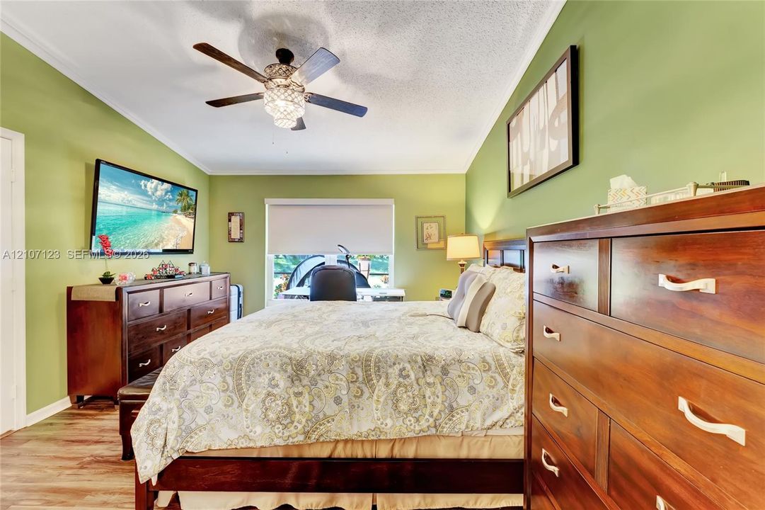Wood-finish flooring, ceiling fan with integrated lighting, and single-pane window with roller shade