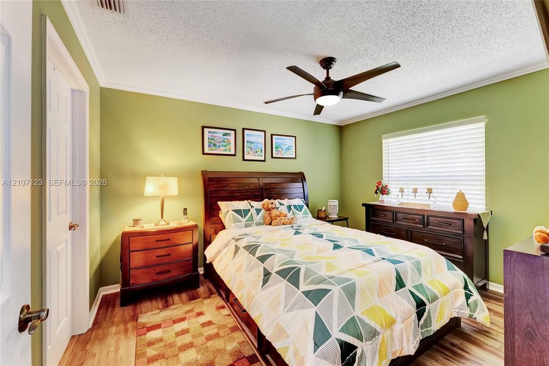 Bedroom featuring wood-finish flooring, a multi-blade ceiling fan with integrated lighting, and horizontal window blinds