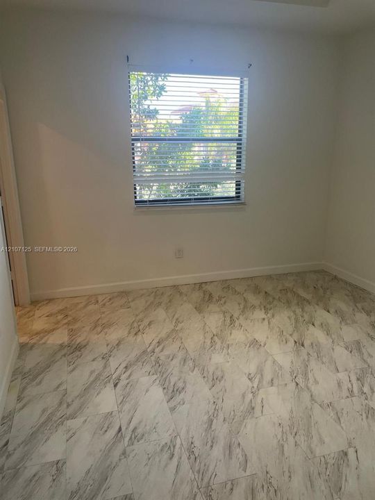 Neutral-toned stone-patterned tile flooring and a single-pane window with horizontal blinds