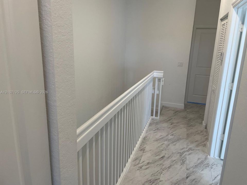 White wooden railing with vertical balusters, stone-finish flooring, and paneled doors