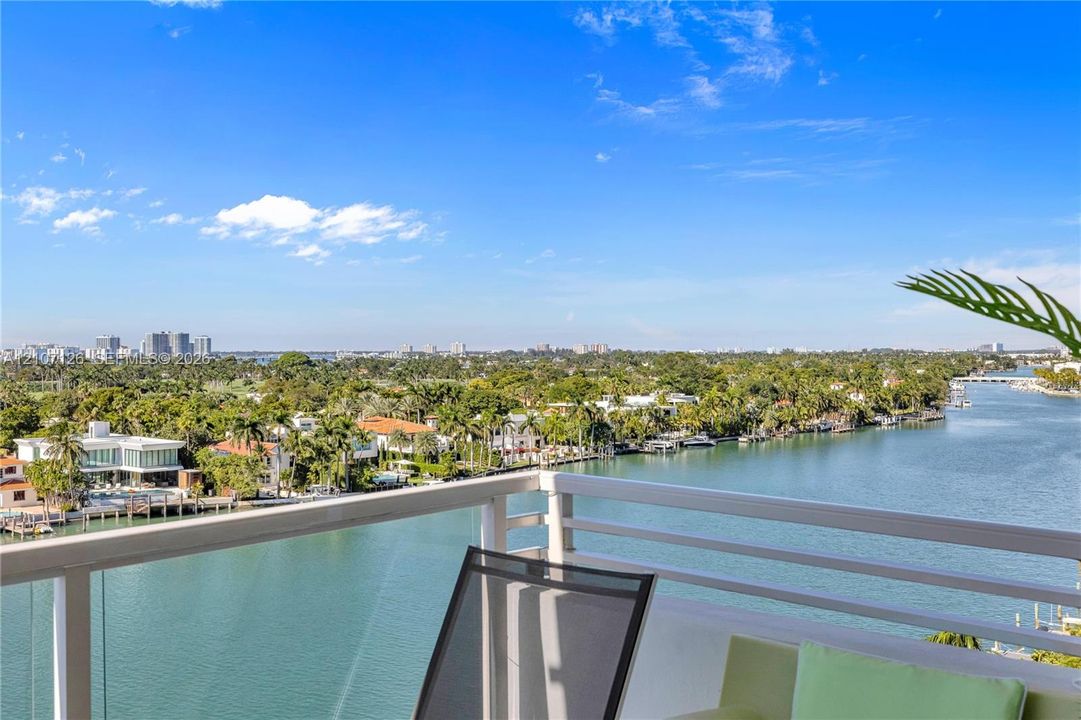 Private balcony featuring a horizontal-rail guard system with glass paneling, overlooking the waterway and landscape