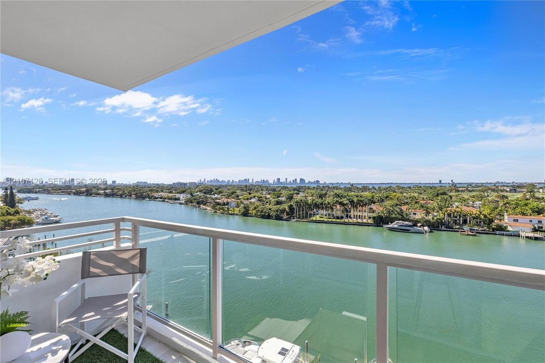 Private balcony featuring a glass panel railing and open-air design with expansive water and city skyline surroundings