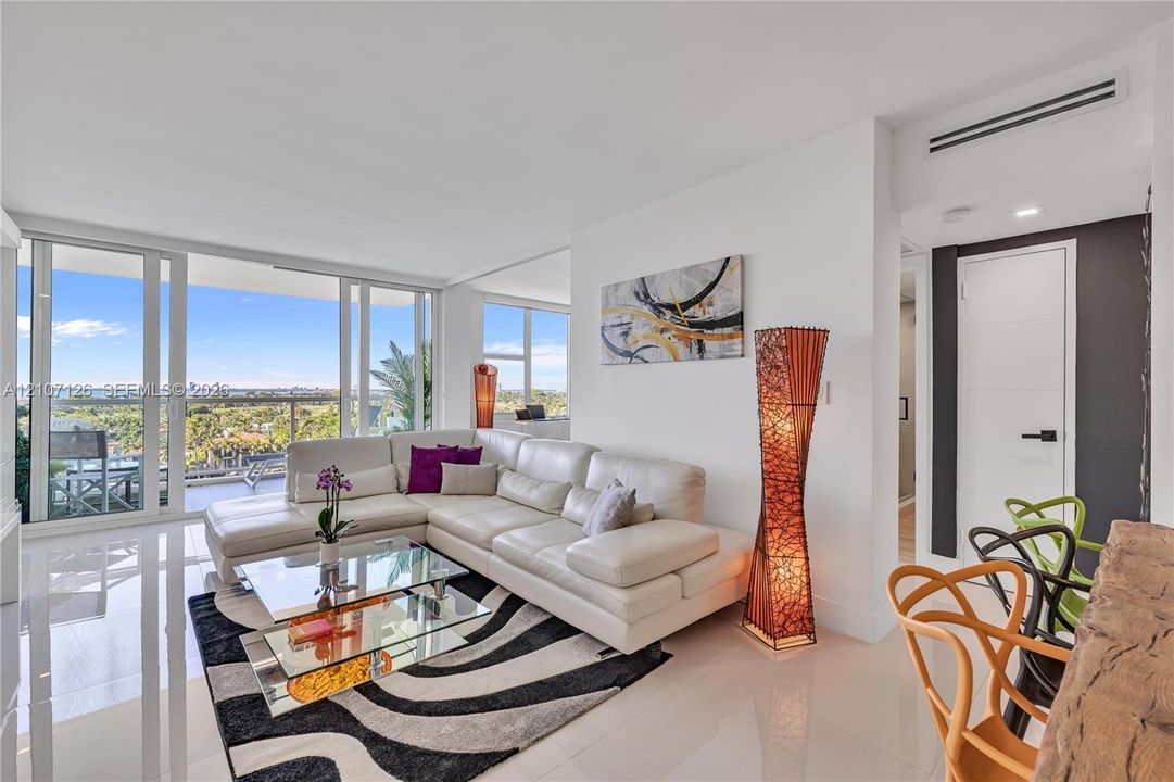 Floor-to-ceiling glass sliding doors, white tile flooring, recessed ceiling lighting, and a neutral color palette