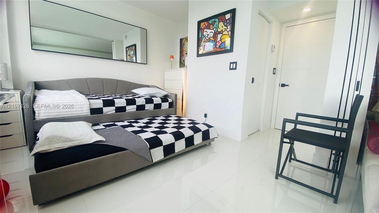 High-gloss tile flooring, large wall-mounted mirror, and multi-panel interior door with matte black hardware