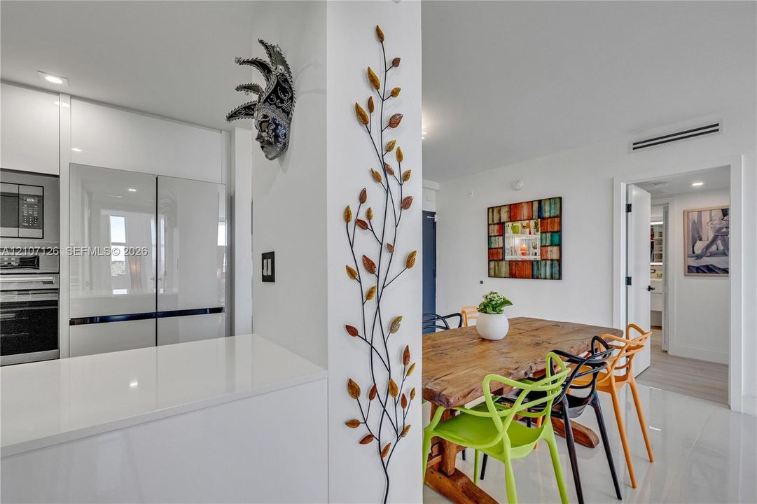 Kitchen area featuring high-gloss cabinetry, a stainless steel refrigerator with double doors, and a smooth white countertop