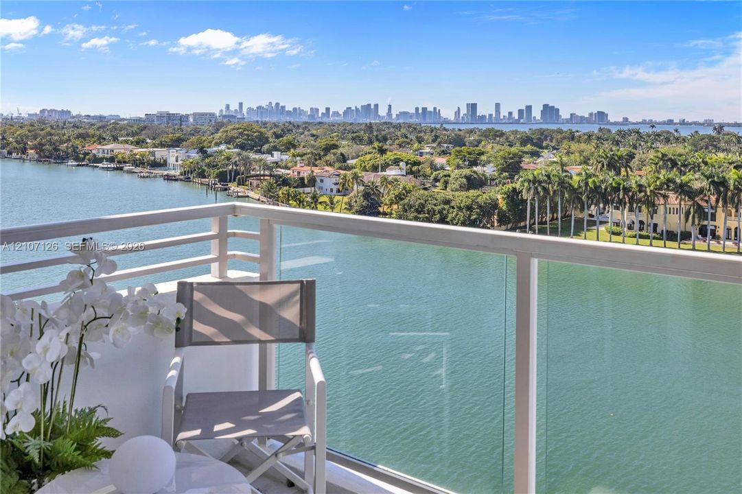 Private balcony with glass panel railing, water frontage, and horizon skyline