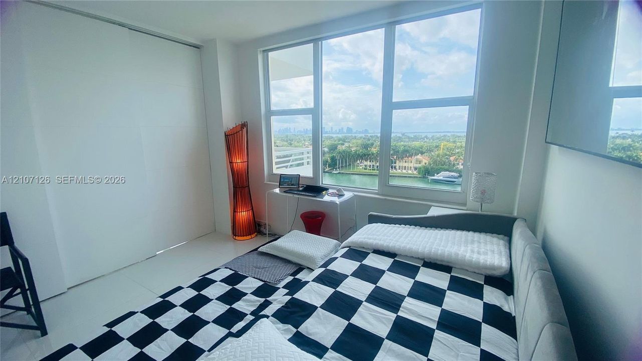 Floor-to-ceiling windows featuring expansive coastal and urban water scenery, complemented by crisp white walls and large-format tile flooring throughout
