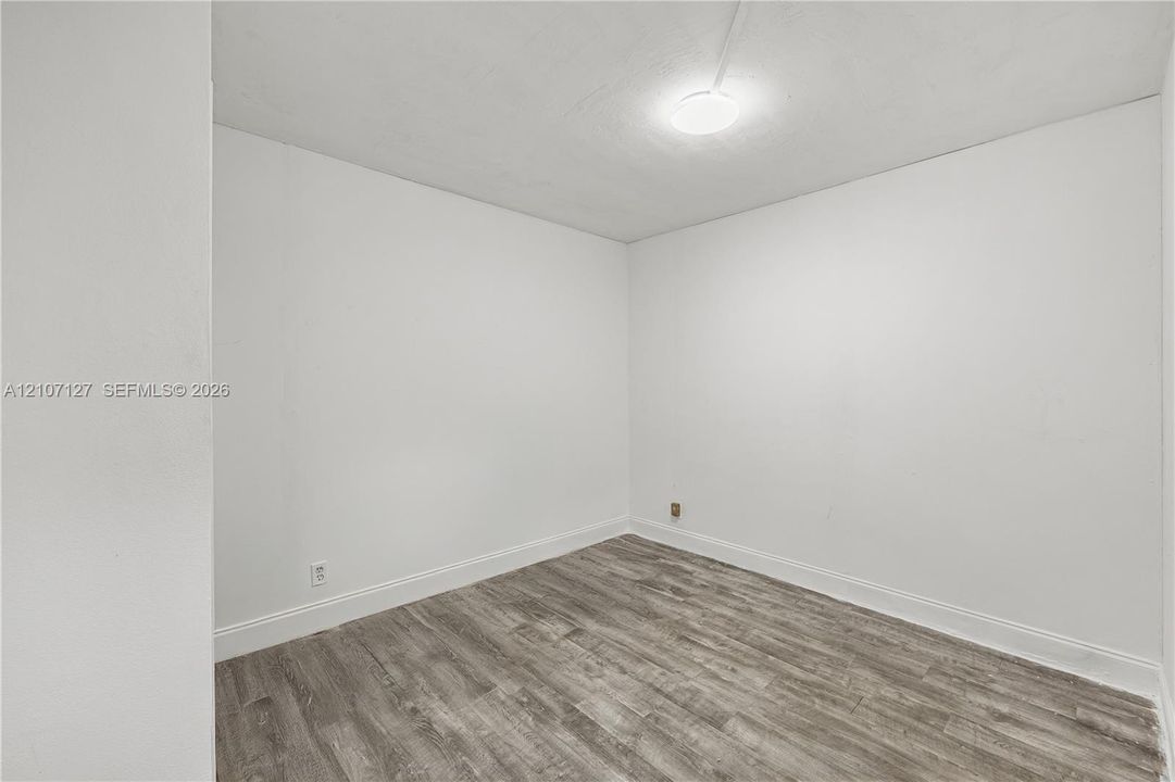 Interior space featuring wood-finish flooring, smooth-finish walls, and a ceiling-mounted light fixture